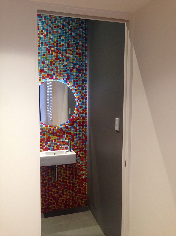 Inspiration for a small modern powder room in Sydney with a one-piece toilet, mosaic tile, porcelain floors, a wall-mount sink, multi-coloured walls and multi-coloured tile.