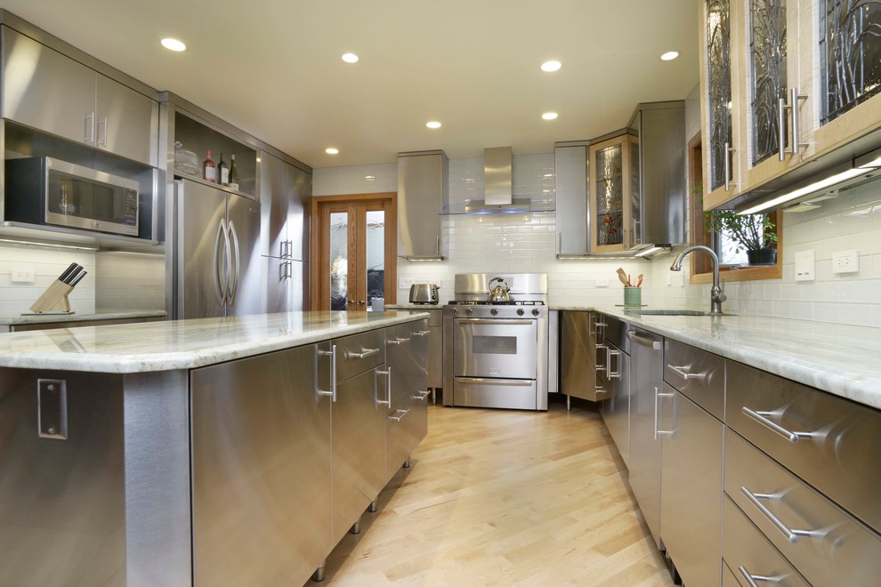 Photo of a mid-sized contemporary eat-in kitchen in Chicago with an undermount sink, flat-panel cabinets, stainless steel cabinets, marble benchtops, white splashback, subway tile splashback, stainless steel appliances, light hardwood floors and with island.