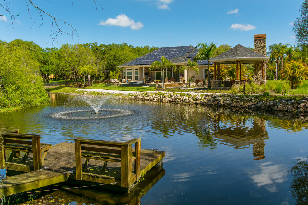 This is an example of an expansive traditional backyard garden in Tampa with with pond.