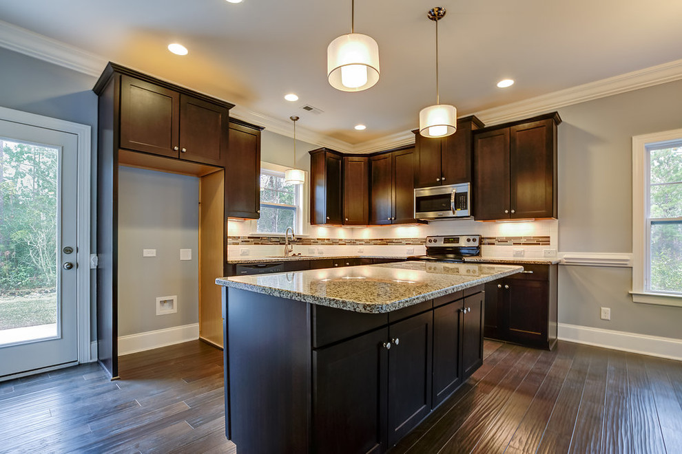 Mid-sized transitional l-shaped dark wood floor and brown floor open concept kitchen photo with an undermount sink, shaker cabinets, dark wood cabinets, granite countertops, white backsplash, porcelain backsplash, stainless steel appliances and an island