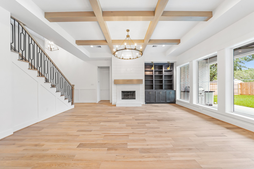 Photo of a medium sized classic open plan games room in Houston with white walls, light hardwood flooring, a standard fireplace, a concrete fireplace surround and exposed beams.