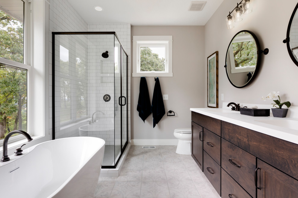 Transitional bathroom in Minneapolis with shaker cabinets, dark wood cabinets, a freestanding tub, white tile, subway tile, grey walls, an undermount sink, grey floor and white benchtops.