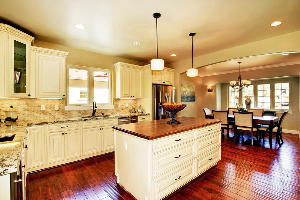 Transitional l-shaped medium tone wood floor eat-in kitchen photo in Cincinnati with raised-panel cabinets, white cabinets, granite countertops, beige backsplash, stainless steel appliances and an island