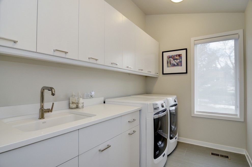 Design ideas for a contemporary single-wall dedicated laundry room in Chicago with an undermount sink, flat-panel cabinets, white cabinets, quartzite benchtops, beige walls, porcelain floors, a side-by-side washer and dryer and white benchtop.
