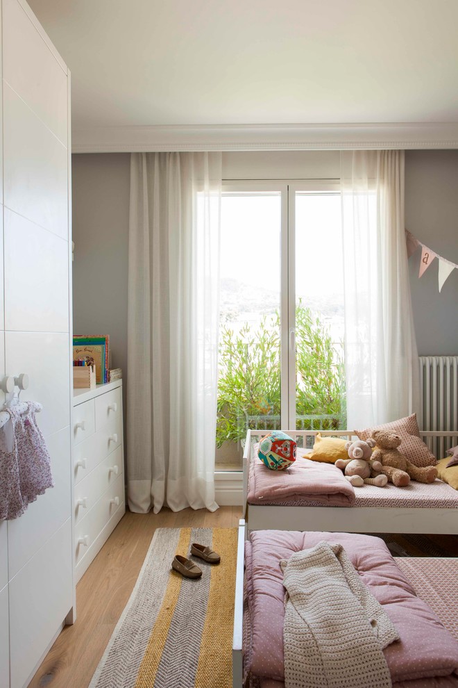 Mid-sized scandinavian kids' bedroom in Other with beige walls and medium hardwood floors for kids 4-10 years old and girls.
