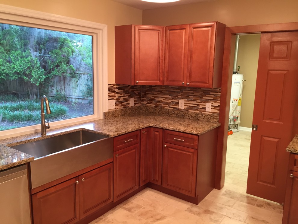 This is an example of a mid-sized traditional u-shaped eat-in kitchen in Atlanta with a farmhouse sink, recessed-panel cabinets, medium wood cabinets, granite benchtops, multi-coloured splashback, mosaic tile splashback, stainless steel appliances, travertine floors and no island.