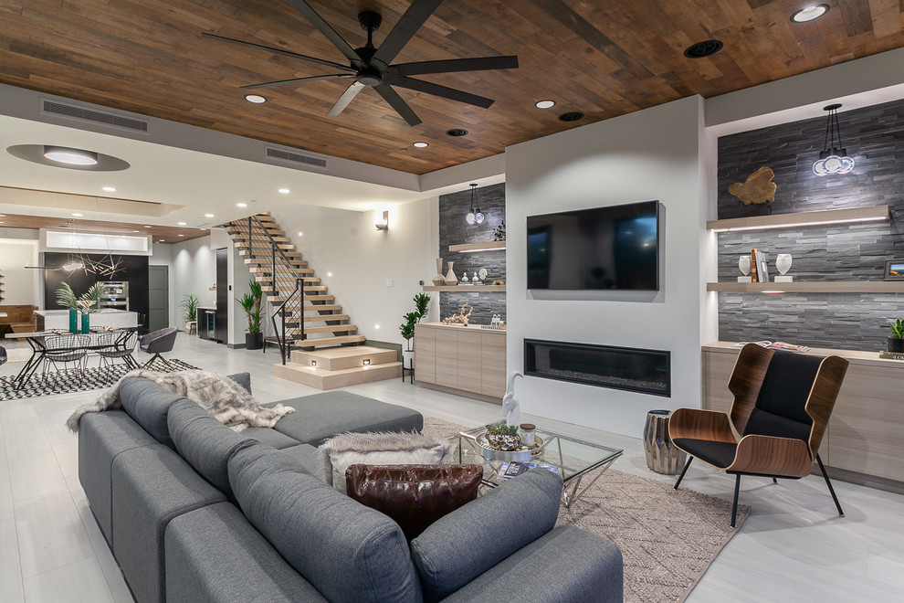 This is an example of a contemporary open concept family room in Orange County with white walls, a ribbon fireplace, a metal fireplace surround, a wall-mounted tv and beige floor.
