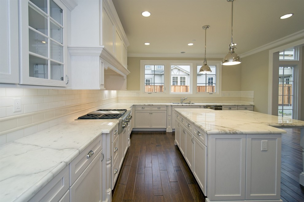 Inspiration for a large traditional l-shaped open plan kitchen in San Francisco with a drop-in sink, recessed-panel cabinets, white cabinets, marble benchtops, multi-coloured splashback, porcelain splashback, stainless steel appliances, medium hardwood floors, with island and multi-coloured floor.