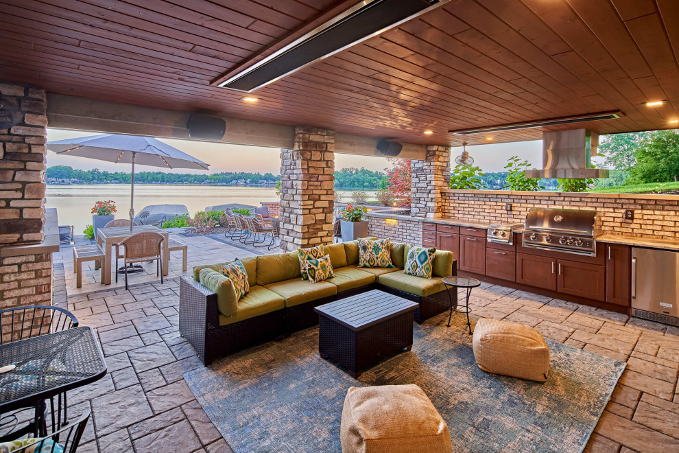 Réalisation d'une grande terrasse arrière marine avec une cuisine d'été, des pavés en béton et une extension de toiture.
