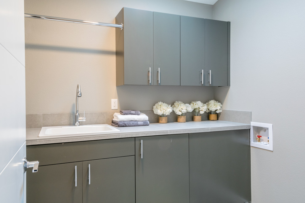 This is an example of a large contemporary galley dedicated laundry room in Portland with an undermount sink, flat-panel cabinets, grey cabinets, grey walls and tile benchtops.