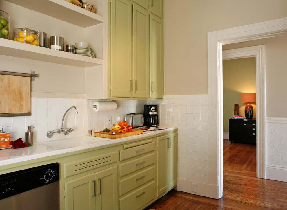 Photo of a small eclectic single-wall kitchen pantry in San Francisco with an undermount sink, flat-panel cabinets, green cabinets, white splashback, ceramic splashback, stainless steel appliances, medium hardwood floors and no island.