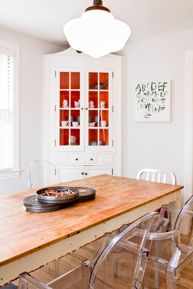 This is an example of an eclectic dining room in New York with white walls and medium hardwood floors.