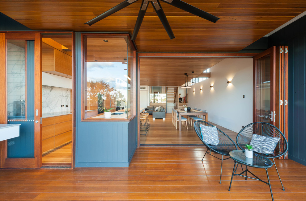 This is an example of a mid-sized contemporary backyard deck in Brisbane with an outdoor kitchen and a roof extension.