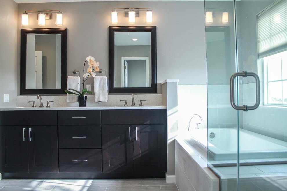 Photo of a large contemporary master bathroom in Philadelphia with shaker cabinets, dark wood cabinets, a drop-in tub, gray tile, grey walls, an undermount sink, engineered quartz benchtops, a corner shower, porcelain tile and porcelain floors.