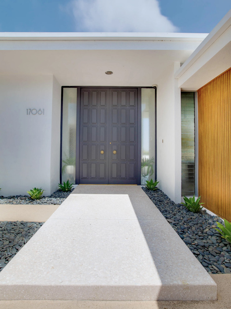 This is an example of a mid-sized midcentury front door in Phoenix with white walls, concrete floors, a double front door, a black front door and beige floor.