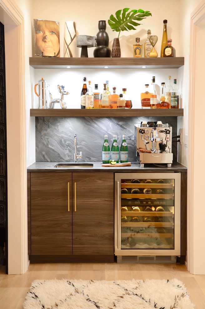 Photo of a mid-sized contemporary single-wall wet bar in New York with flat-panel cabinets, medium wood cabinets, soapstone benchtops, grey splashback, light hardwood floors, an undermount sink, beige floor and grey benchtop.