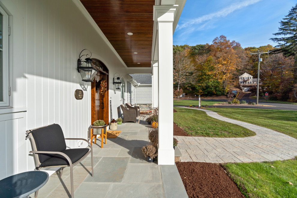 Idées déco pour un grand porche d'entrée de maison avant campagne avec des colonnes, des pavés en béton et une extension de toiture.