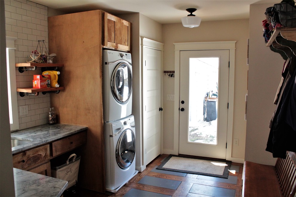 Design ideas for a mid-sized country l-shaped utility room in New York with an undermount sink, shaker cabinets, light wood cabinets, quartzite benchtops, beige walls, ceramic floors and a stacked washer and dryer.