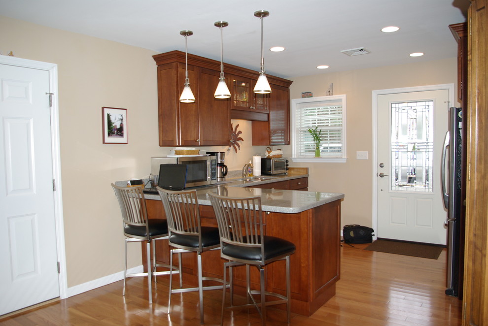 Inspiration for a mid-sized traditional l-shaped eat-in kitchen in Philadelphia with an undermount sink, shaker cabinets, medium wood cabinets, recycled glass benchtops, stainless steel appliances, light hardwood floors and a peninsula.