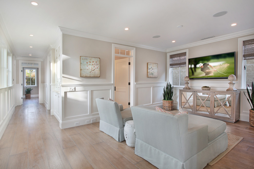 Photo of a beach style family room in Orange County with beige walls, a wall-mounted tv and light hardwood floors.