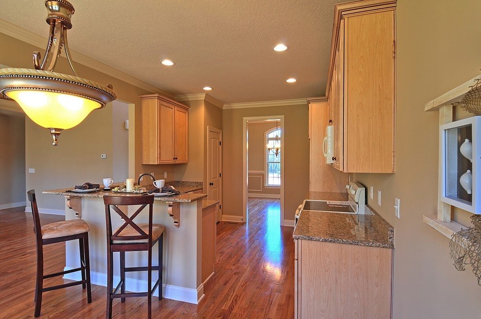 Eat-in kitchen - transitional l-shaped eat-in kitchen idea with an undermount sink, flat-panel cabinets, light wood cabinets, granite countertops and colored appliances