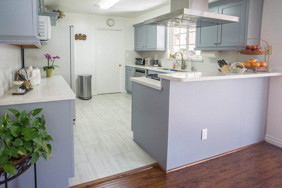 Mid-sized transitional l-shaped porcelain tile and white floor enclosed kitchen photo with an undermount sink, shaker cabinets, gray cabinets, quartz countertops, white backsplash, stone slab backsplash, stainless steel appliances, no island and white countertops