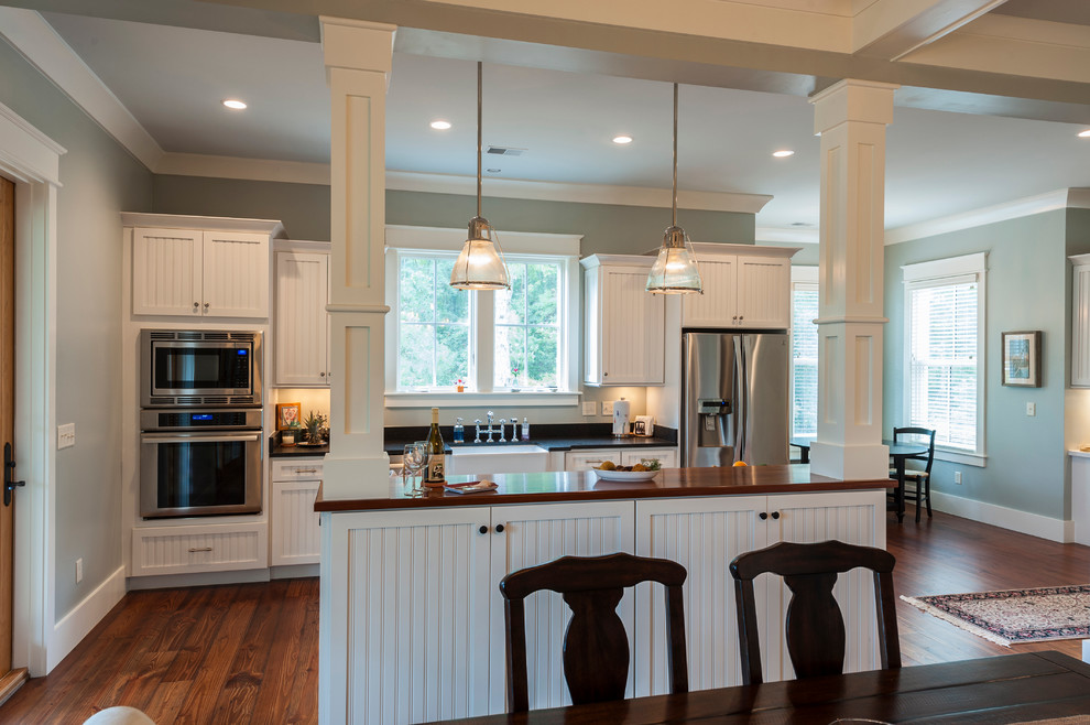 Inspiration for a mid-sized country single-wall eat-in kitchen in Charleston with stainless steel appliances, medium hardwood floors, with island, a farmhouse sink, louvered cabinets, white cabinets and wood benchtops.