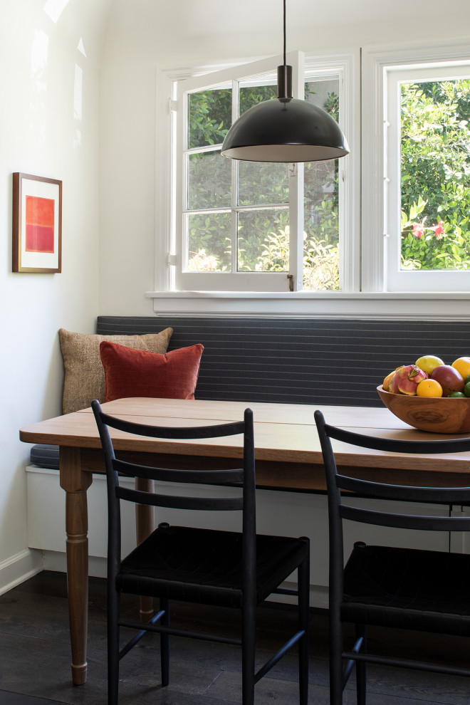 Exemple d'une petite salle à manger éclectique avec une banquette d'angle, un mur blanc, parquet foncé et un sol marron.