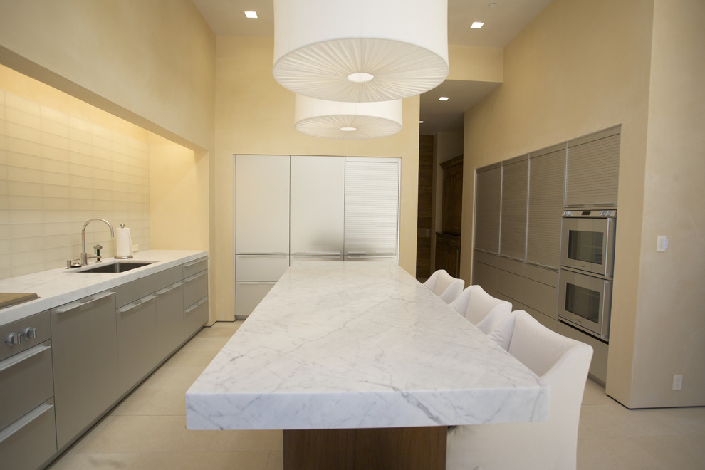 Inspiration for a contemporary u-shaped eat-in kitchen in San Francisco with stainless steel appliances, an undermount sink, flat-panel cabinets, stainless steel cabinets, marble benchtops, white splashback, glass tile splashback and ceramic floors.