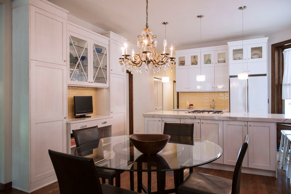Example of a mid-sized transitional l-shaped medium tone wood floor eat-in kitchen design in Chicago with an undermount sink, shaker cabinets, white cabinets, quartz countertops, yellow backsplash, ceramic backsplash, white appliances and an island