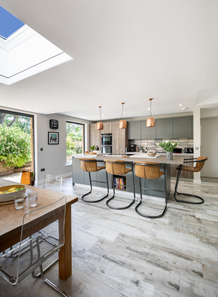 This is an example of a large contemporary single-wall eat-in kitchen in Other with flat-panel cabinets, with island, grey floor, brown benchtop, wood benchtops, light hardwood floors, black cabinets, black appliances, a double-bowl sink, grey splashback and cement tile splashback.
