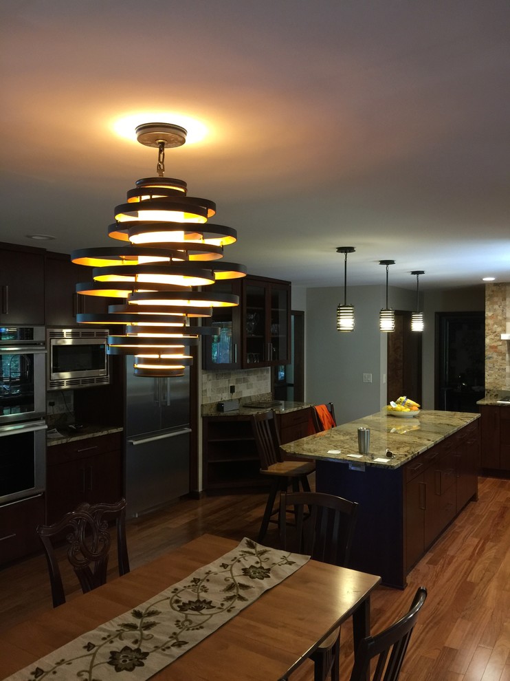 Example of a large transitional u-shaped medium tone wood floor eat-in kitchen design in Chicago with stainless steel appliances, an undermount sink, flat-panel cabinets, dark wood cabinets, granite countertops, beige backsplash, stone tile backsplash and an island