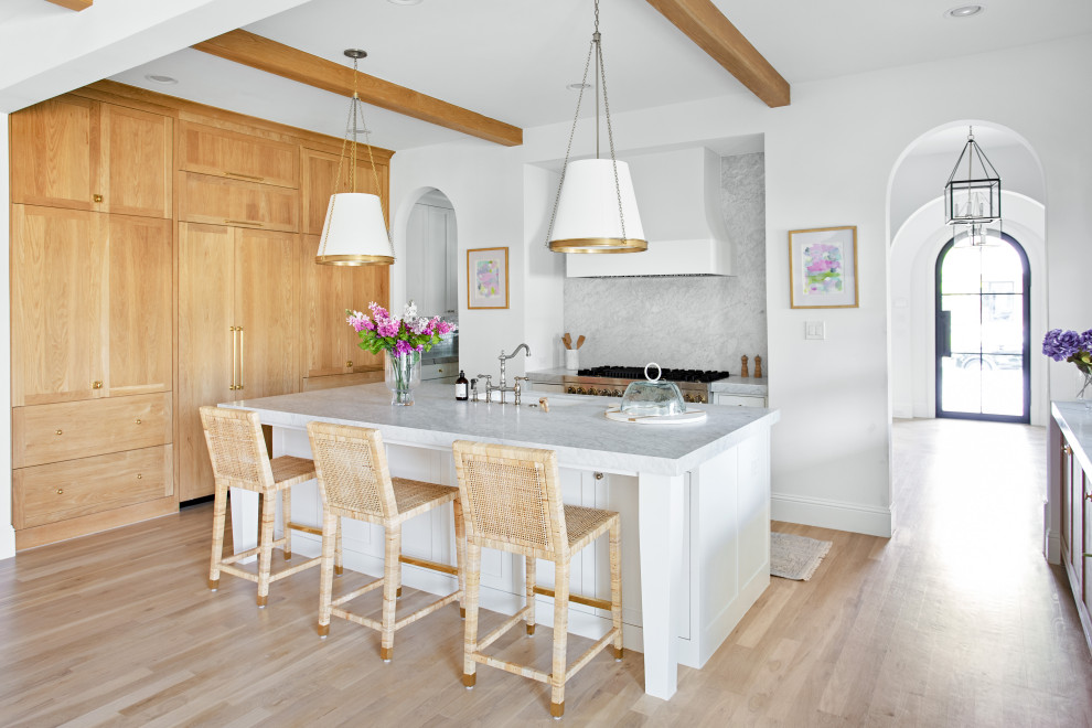 Open concept kitchen - large transitional l-shaped light wood floor, brown floor and exposed beam open concept kitchen idea in Dallas with an undermount sink, shaker cabinets, white cabinets, marble countertops, white backsplash, marble backsplash, paneled appliances, an island and white countertops