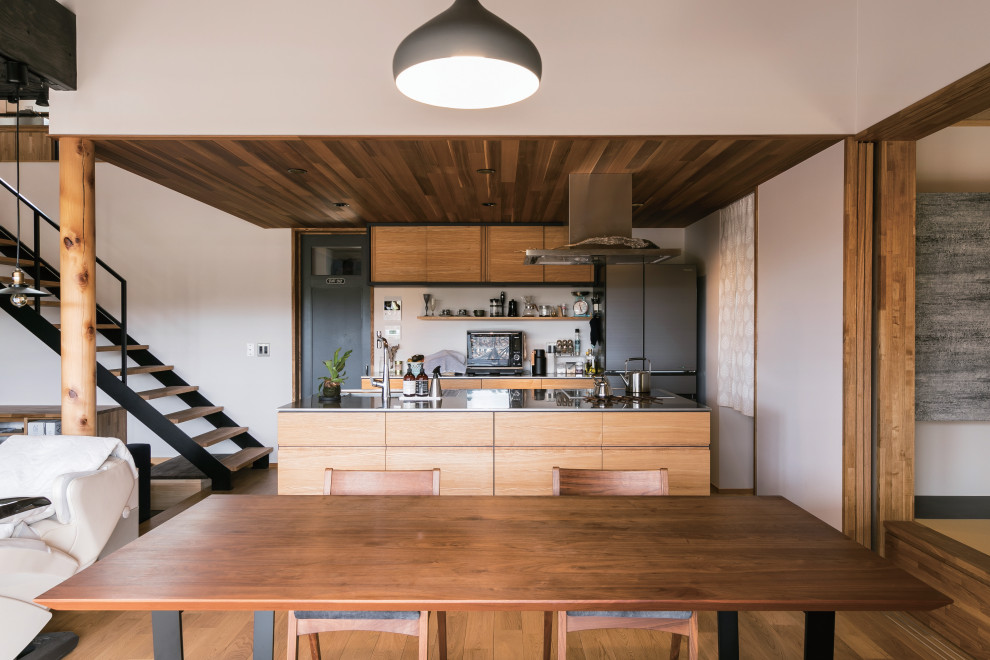 Foto på ett nordiskt linjärt kök med öppen planlösning, med en integrerad diskho, släta luckor, skåp i mellenmörkt trä, bänkskiva i rostfritt stål, integrerade vitvaror, mellanmörkt trägolv, en köksö och beiget golv