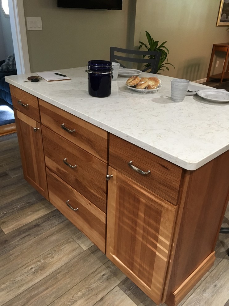 Inspiration for a mid-sized transitional l-shaped laminate floor and gray floor eat-in kitchen remodel in Boston with an undermount sink, shaker cabinets, light wood cabinets, quartz countertops, multicolored backsplash, glass sheet backsplash, stainless steel appliances, an island and white countertops
