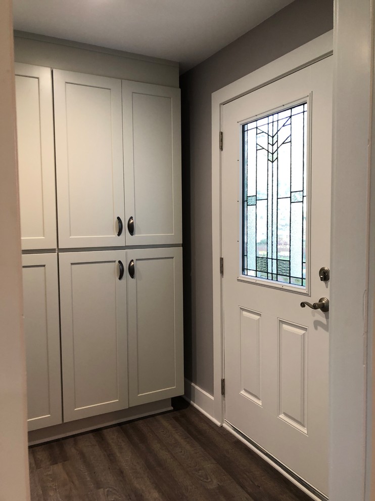 This is an example of a mid-sized eclectic utility room in Atlanta with shaker cabinets, grey cabinets, grey walls, vinyl floors, a stacked washer and dryer and grey floor.
