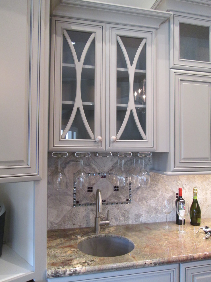 Huge transitional l-shaped porcelain tile open concept kitchen photo in Phoenix with an undermount sink, raised-panel cabinets, gray cabinets, granite countertops, gray backsplash, stone tile backsplash, stainless steel appliances and an island