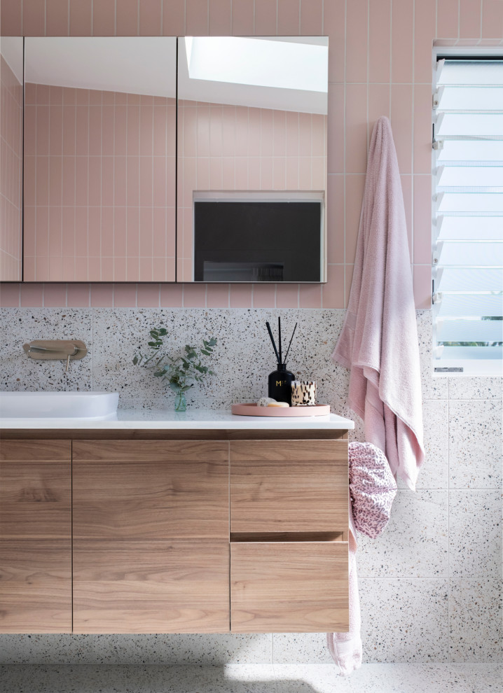 Идея дизайна: большая ванная комната в стиле модернизм с плоскими фасадами, коричневыми фасадами, отдельно стоящей ванной, открытым душем, унитазом-моноблоком, розовой плиткой, плиткой кабанчик, разноцветными стенами, полом из терраццо, душевой кабиной, накладной раковиной, мраморной столешницей, серым полом, душем с распашными дверями, белой столешницей, нишей, тумбой под одну раковину и подвесной тумбой