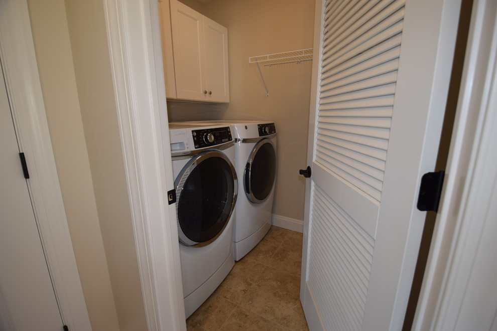 Inspiration for a beach style galley dedicated laundry room in New York with recessed-panel cabinets, white cabinets, white walls, ceramic floors and a side-by-side washer and dryer.
