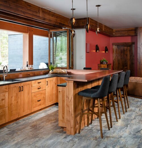 Inspiration for a country u-shaped seated home bar in Other with an undermount sink, shaker cabinets, medium wood cabinets, copper benchtops, porcelain floors and grey floor.