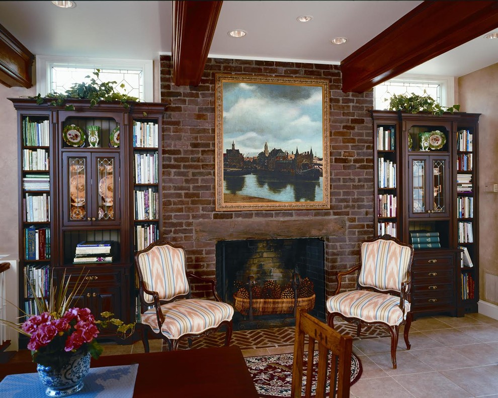 This is an example of a mid-sized traditional home office in DC Metro with a library, beige walls, porcelain floors, a standard fireplace, a brick fireplace surround, a freestanding desk and beige floor.