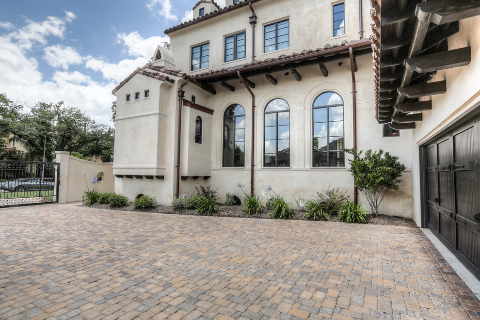 This is an example of a large mediterranean two-storey stucco beige house exterior in Houston with a hip roof and a tile roof.