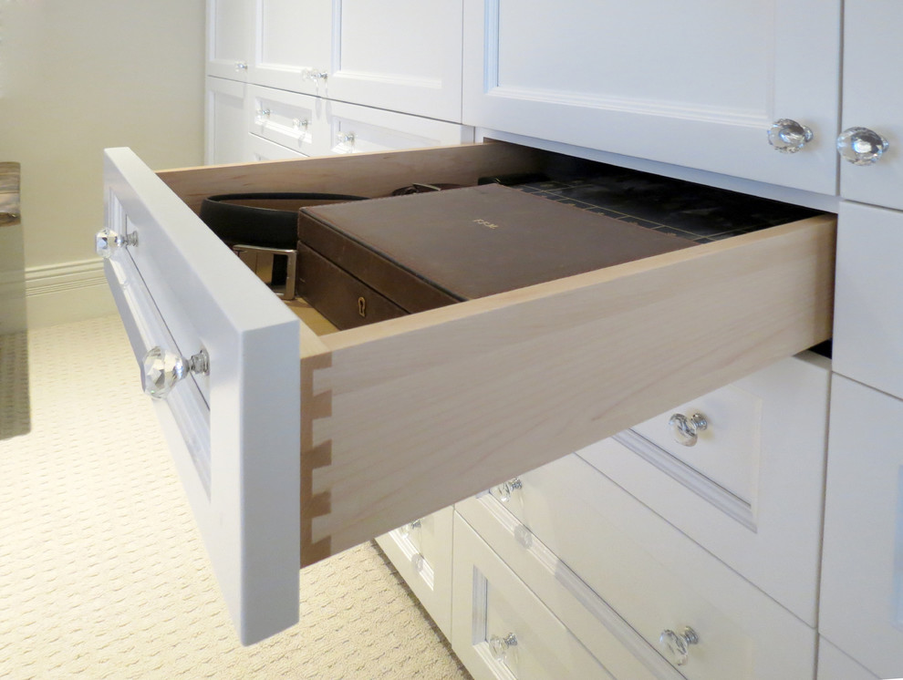 This is an example of a small transitional gender-neutral built-in wardrobe in Toronto with recessed-panel cabinets, white cabinets and carpet.