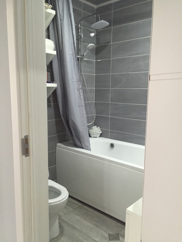 This is an example of a mid-sized contemporary 3/4 bathroom in Other with furniture-like cabinets, white cabinets, a freestanding tub, a shower/bathtub combo, a one-piece toilet, gray tile, ceramic tile, grey walls, ceramic floors, a drop-in sink, onyx benchtops, grey floor and a shower curtain.