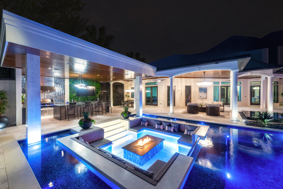 Design ideas for a large contemporary backyard custom-shaped infinity pool in Tampa with with privacy feature and tile.