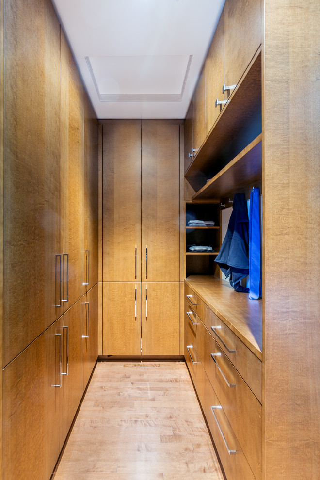 This is an example of a contemporary gender-neutral walk-in wardrobe in Ottawa with flat-panel cabinets, medium wood cabinets and beige floor.