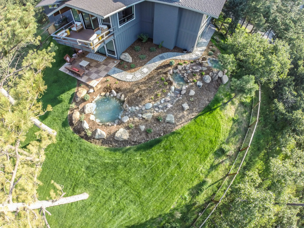 This is an example of a large eclectic backyard partial sun garden for summer in Denver with with pond, mulch and a wood fence.