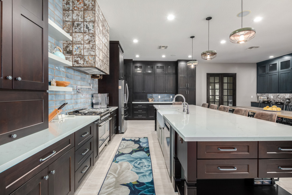 Inspiration for a huge rustic l-shaped porcelain tile eat-in kitchen remodel in Phoenix with a farmhouse sink, shaker cabinets, brown cabinets, quartz countertops, blue backsplash, subway tile backsplash, an island and white countertops