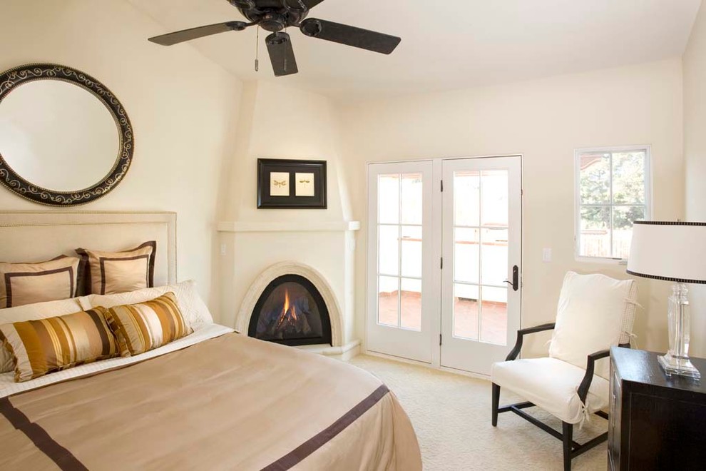 Mid-sized mediterranean master bedroom in Santa Barbara with white walls, a corner fireplace, carpet, a plaster fireplace surround and beige floor.