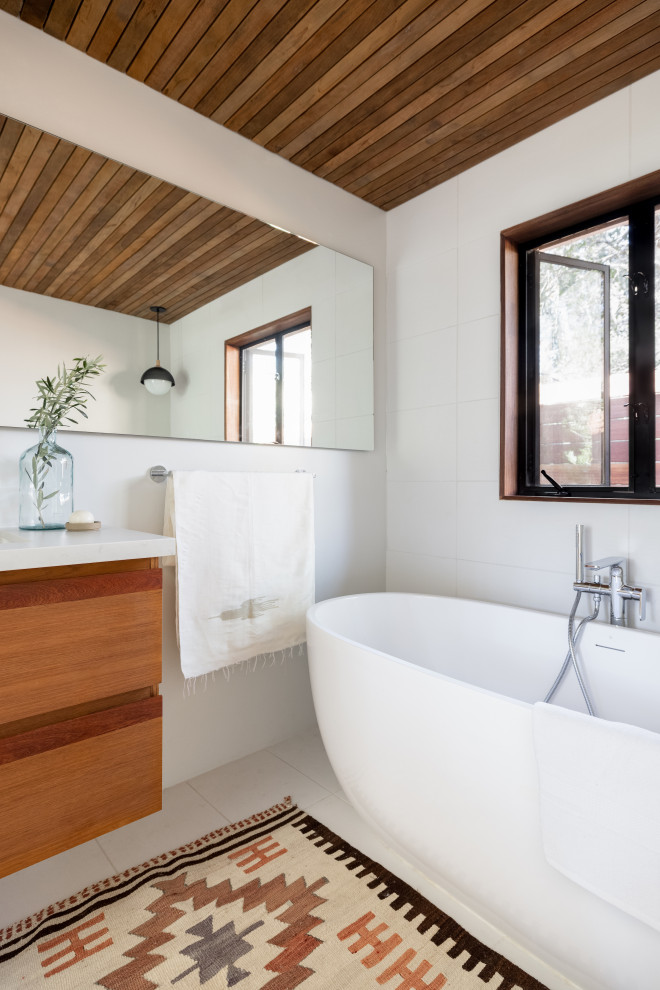 ロサンゼルスにあるラグジュアリーな小さな北欧スタイルのおしゃれな浴室 (中間色木目調キャビネット、置き型浴槽、白い洗面カウンター、洗面台1つ、フローティング洗面台、板張り天井) の写真